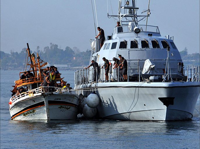 epa03834390 A 'Guardia di Finanza' ship flanks an overcrowded boat with more than 120 refugees believed to be from Syria who were rescued when migrant boats arrived at the coast of Syracuse, Sicily island, Italy, 23 August 2013. Rescues, pickups and landings have been occurring almost every day over recent weeks. Each year, especially during the warm summer, thousands fleeing poverty or persecution in Africa, the Middle East or elsewhere try to reach Europe over the southern Mediterranean Sea. EPA/VALENTINO CILMI