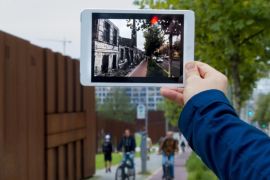 Developer Robin von Hardenberg holds a tablet computer that runs his Timetraveler augmented reality app at Bernauer Street in Berlin, September 26, 2014. The app superimposes historic footage of scenes that unfolded when the Berlin Wall was erected in 1961 onto today's location when pointing the tablet at the specific spot. Berlin marks this year the 25th anniversary of the building of border fortification that divided the east and the west of the city. REUTERS/Thomas Peter (GERMANY - Tags: SCIENCE TECHNOLOGY SOCIETY ANNIVERSARY)