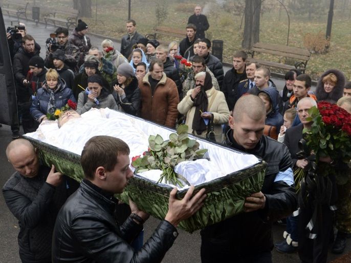 People carry coffins with the bodies of Andrey Yeliseyev and Daniil Kuznetsov for a burial service in a church of the eastern Ukrainian city of Donetsk on November 7, 2014. On November 5, heavy bombardments raged around Donetsk's former international airport, where government forces are holding out against besieging separatists. One shell landed in a nearby school football field and killed two boys aged 14 and 18. AFP PHOTO/ ALEXANDER KHUDOTEPLY