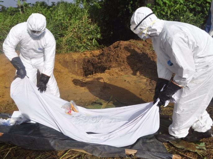 In this photo taken on Monday, Oct. 27, 2014, health workers prepare to place the body of a man who was suspected of dying from the Ebola virus into a grave on the outskirts of Monrovia, Liberia. The head of Africa’s continental body did not get to an Ebola-hit country until last week - months after alarm bells first rang and nearly 5,000 deaths later. (AP Photo/Abbas Dulleh)