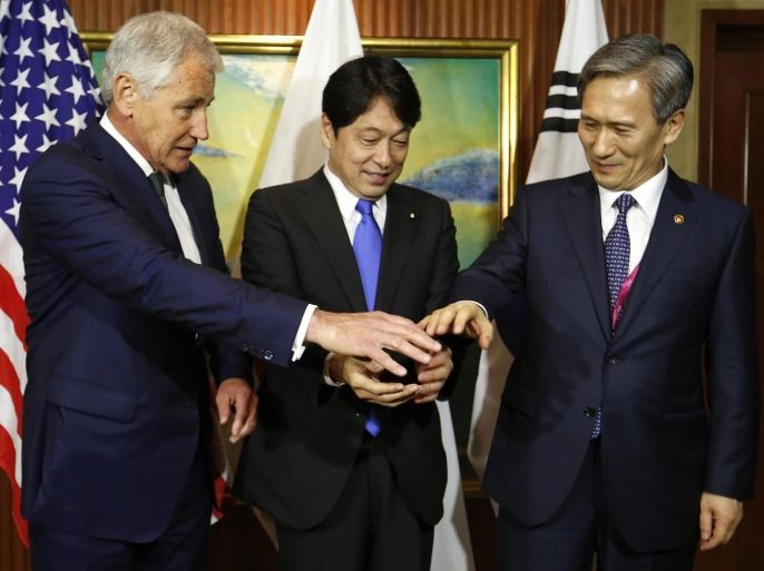 US Defense Secretary Chuck Hagel (L) join hands with South Korean Defense Minister Kim Kwan-jin (L) and Japanese Defense Minister Itsunori Onodera (C) during a trilateral meeting between US, Japan and South Korea on the second day of The International Institute for Strategic Studies (IISS) 13th Asia Security Summit in Singapore, 31 May 2014. The IISS Asia Security Summit is an annual gathering of defense officials in the Asia-Pacific dubbed the Shangri-La Dialogue in honor of the hotel where the event is held.