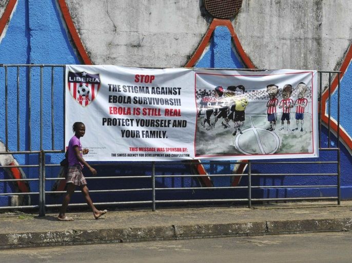 A woman walks pass an Ebola virus awareness campaign poster in Monrovia, December 8, 2014. Liberia is the country hardest hit by the epidemic and has recorded more than 3,000 deaths out of a total from Liberia, Sierra Leone and Guinea of 6,055 victims, according to World Health Organization figures. REUTERS/James Giahyue (LIBERIA - Tags: HEALTH SOCIETY DISASTER)