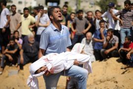 ATTENTION EDITORS - VISUAL COVERAGE OF SCENES OF INJURY OR DEATHRNPS - REUTERS NEWS PICTURE SERVICE - PICTURES OF THE YEAR 2014A Palestinian man reacts as he carries the body of a girl from the Abu Nejim family, whom medics said was killed along with other eight family members by an Israeli air strike, before her burial at a cemetery in Beit Lahiya in the northern Gaza Strip, in this August 4, 2014 file photo. REUTERS/Mohammed Salem/Files (GAZA - Tags: POLITICS CIVIL UNREST TPX IMAGES OF THE DAY) TEMPLATE OUT
