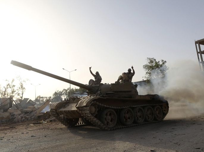Fighters from the Benghazi Shura Council, which includes former rebels and militants from al Qaeda-linked Ansar al-Sharia, gesture on top of a tank next to the camp of the special forces in Benghazi July 30, 2014. On Wednesday, the eastern city of Benghazi was quieter after Islamist fighters and allied militia forces overran a special forces army base in the city in a major blow to a military campaign against Islamist militants there. The self-declared Benghazi Shura Council forces took over the base on Tuesday after fighting involving rockets and warplanes that killed at least 30 people. REUTERS/Stringer (LIBYA - Tags: CIVIL UNREST POLITICS)