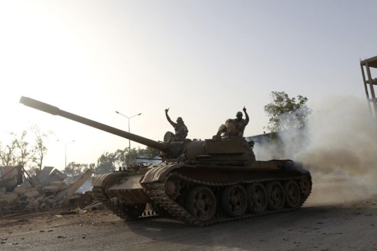 Fighters from the Benghazi Shura Council, which includes former rebels and militants from al Qaeda-linked Ansar al-Sharia, gesture on top of a tank next to the camp of the special forces in Benghazi July 30, 2014. On Wednesday, the eastern city of Benghazi was quieter after Islamist fighters and allied militia forces overran a special forces army base in the city in a major blow to a military campaign against Islamist militants there. The self-declared Benghazi Shura Council forces took over the base on Tuesday after fighting involving rockets and warplanes that killed at least 30 people. REUTERS/Stringer (LIBYA - Tags: CIVIL UNREST POLITICS)