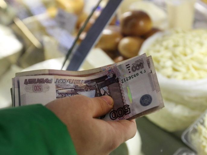 A customer counts out ruble banknotes at a stall selling dairy products inside the Dorogomilovsky food market in Moscow, Russia, on Tuesday, Dec. 23, 2014. The ruble's rout, sparked by falling oil prices and sanctions imposed on businesses including OAO Sberbank, prompted Russians to begin buying luxury goods from Porsche sports cars to Tiffany rings to preserve the value of their savings.