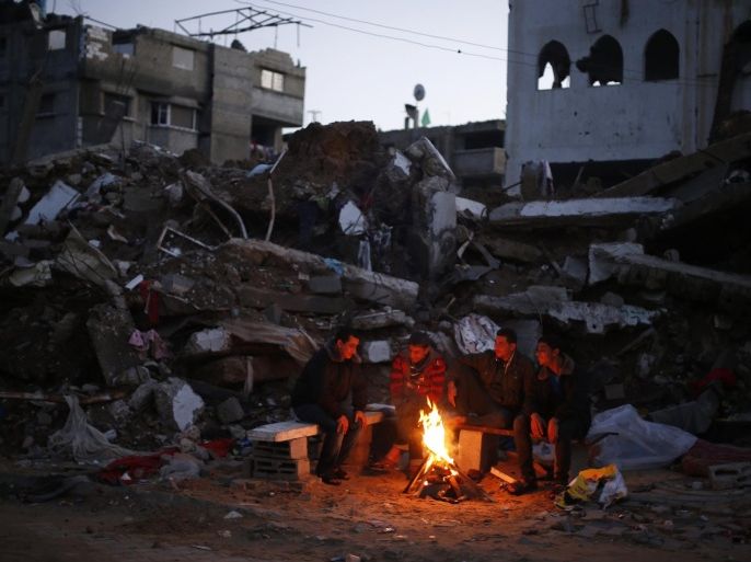 Palestinians warm themselves by a fire near the ruins of houses which witnesses said were destroyed by Israeli shelling during the most recent conflict between Israel and Hamas, in the east of Gaza City December 1, 2014. According to housing minister Mufeed al-Hasayna, Gaza needs 8,000 tonnes of cement a day to meet demand. A new system set up with the United Nations to comply with Israeli requirements lets through at most 2,000, he said. At that rate, reconstruction would take more than 30 years, said Hasayna, one of four members of the unity government based in Gaza rather than the West Bank. Since the war, electricity has been partially restored so that power is now cut for only eight hours a day. Sewage and water treatment plants are mostly working again, although there is still almost no drinking water. But in terms of clearing the vast mountains of rubble and mangled steel, rebuilding homes and patching up smashed roads, bridges and other infrastructure, next to nothing has happened. REUTERS/Mohammed Salem (GAZA - Tags: POLITICS CIVIL UNREST BUSINESS CONSTRUCTION CONFLICT SOCIETY TPX IMAGES OF THE DAY)