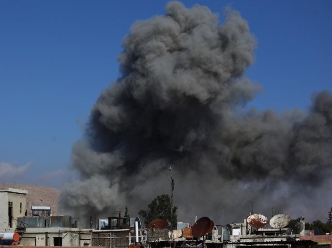 Smoke rises from buildings following a reported airstrike by government forces on a civilian neighourhood of the besieged rebel-held town of Douma on December 23, 2014. Douma, a rebel bastion northeast of the capital, has been under government siege for more than a year, with residents facing dwindling food and medical supplies. AFP PHOTO / ABD DOUMANY