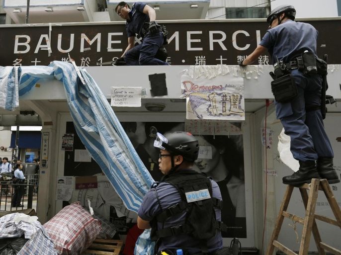 Police officers remove obstacles at a tram stop during a clearance at the last "Occupy" protest site blocking a main road at Causeway Bay shopping district in Hong Kong December 15, 2014. Hong Kong authorities started to clear the last of three pro-democracy protest sites on Monday, marking the end of demonstration camps in the city that have blocked streets for more than two months. REUTERS/Athit Perawongmetha (CHINA - Tags: POLITICS BUSINESS EDUCATION CRIME LAW)