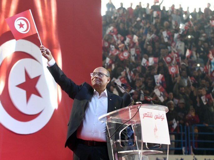 Tunisian President and presidential candidate, Moncef Marzouki waves the national flag during a campaign meeting on December 14, 2014 in Tunis. Marzouki came second to Beji Caid Essebsi in the first round of polling last month, and will face him again on December 21. AFP PHOTO / FETHI BELAID