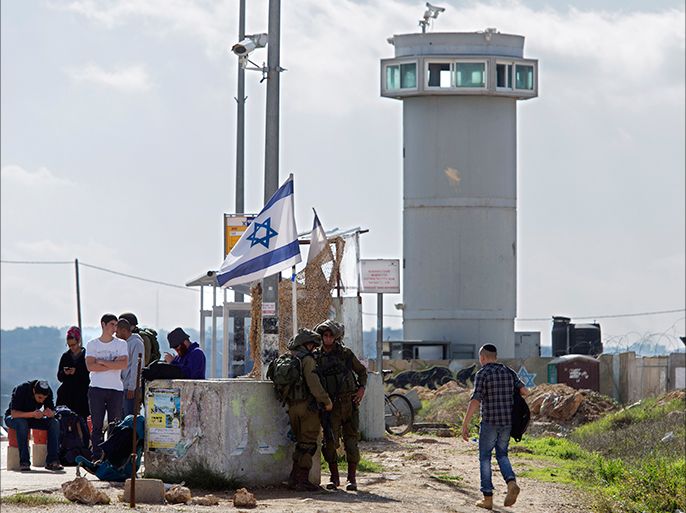 epa04510689 Israeli soldiers at the Gush Etzion exchange where Jewish settlers wait for rides near a guard tower equipped with video cameras at the area where a Palestinian woman reportedly stabbed an Israeli soldier outside the Jewish settlement of Efrat in the Gush Etzion settlement area in the West Bank, south of Jerusalem, 01 December 2014. According to media reports, the Palestinian woman from the nearby village of Fajar was shot and is in serious condition in an Israeli hospital. EPA/JIM HOLLANDER