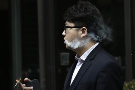 An employee with a cigarette at hand exhales smoke outside a cafe in Beijing, November 25, 2014. China, the world's biggest tobacco market, is considering a draft regulation that would ban indoor smoking, limit outdoor smoking and end tobacco advertising, the state-run Xinhua news agency has reported. REUTERS/Jason Lee (CHINA - Tags: HEALTH BUSINESS)