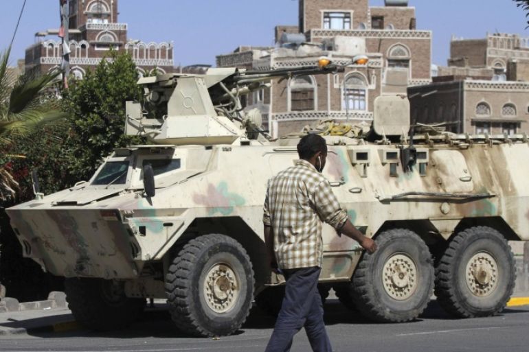 A man walks past an armoured vehicle belonging to Shi'ite Houthi fighters, which was seized from the army recently, near the Defence Ministry compound in Sanaa December 17, 2014. REUTERS/Mohamed al-Sayaghi (YEMEN - Tags: MILITARY CIVIL UNREST)