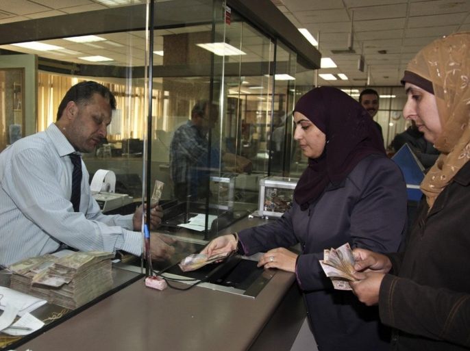 Customers (R) deposit Jordanian dinars at the Jordan Islamic Bank in Amman May 19, 2010. Jordan Islamic Bank, the country's largest Islamic lender, expects double-digit growth this year as it taps fast-rising demand for Sharia-compliant products in an otherwise sluggish overall market, its CEO Musa Abdelaziz Shihadeh said. To match Interview JORDAN-BANK.