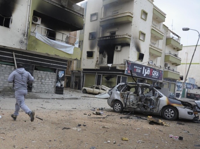 ADVANCE TO GO WITH MIDEAST-FOUR TURBULENT YEARS - FILE - In this Oct. 30, 2014 file photo, a man runs between buildings damaged during clashes between Libyan military soldiers and Islamic extremist militias in Benghazi, Libya. (AP Photo/Mohammed el-Sheikhy, File)