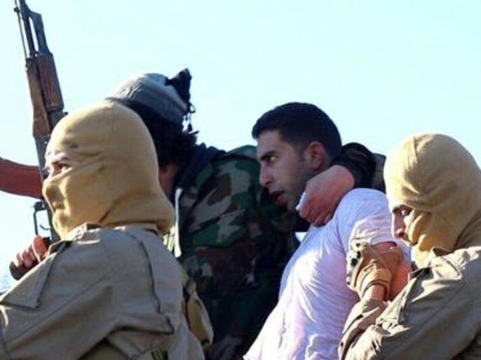 This image posted by the Raqqa Media Center, which monitors events in territory controlled by Islamic State militants with the permission of the extremist group, shows militants with a captured pilot, center right, wearing a white shirt in Raqqa, Syria, Wednesday, Dec. 24, 2014. Islamic State group militants captured a Jordanian pilot, Mu'ath Safi Yousef al-Kaseasbeh, after his warplane went down in Syria, Jordan said Wednesday, the first such capture since the international coalition's air campaign against the group began. The pilot's family confirmed that it is al-Kaseasbeh shown in the image. (AP Photo/Raqqa Media Center)