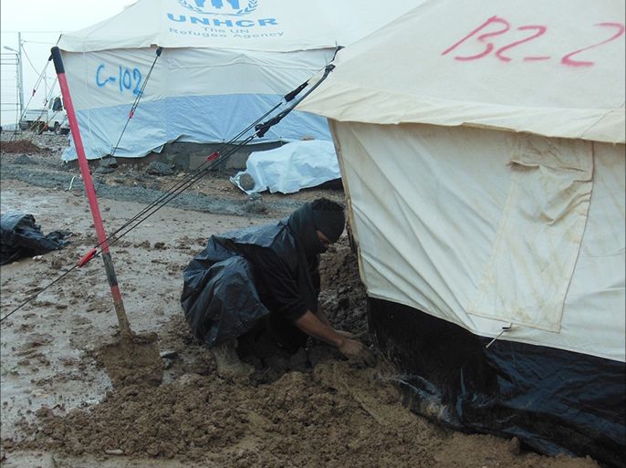 نازح يصلح خيمة من اضرار الامطار - تفاقم معاناة النازحين في دهوك مع فصل الشتاء