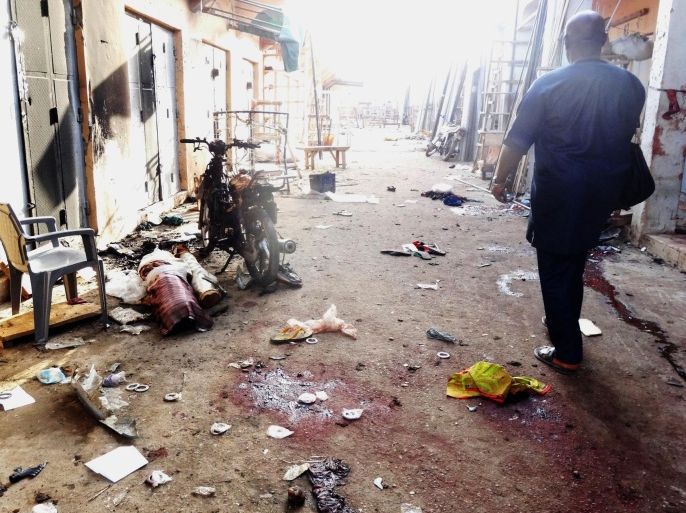 A man walks past blood stains and rubble after twin suicide blasts at Kantin Kwari textile market in northern Nigeria's commercial city of Kano on December 10, 2014. Two female suicide bombers killed at least four people at a busy market in northern Nigeria's largest city Kano, less than two weeks after a horrific attack at the city's central mosque. Kano state police commissioner Adenrele Shinaba said the blast at the Kantin Kwari market in Kano city was 'a twin suicide bombing carried out by two young girls in hijab'. AFP PHOTO / AMINU ABUBAKAR