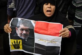 A supporter of the Muslim Brotherhood movement holds a placard showing ousted president Mohamed Morsi during a demonstration on January 24, 2015 in the Cairo district of Heliopolis, ahead of the 4th anniversary of the outbreak of an 18-day uprising that drove former president Hosni Mubarak from power 2011. Morsi's backers regularly attempt anti-government protests that often end in violence. AFP PHOTO / MOHAMED EL-SHAHED