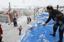 A Syrian refugee removes snow from tents during snowfall at a makeshift settlement in Bar Elias, in the Bekaa valley, January 7, 2015. A storm buffeted the Middle East with blizzards, rain and strong winds on Wednesday, keeping people at home across much of the region and raising concerns for Syrian refugees facing freezing temperatures in flimsy shelters. REUTERS/Mohamed Azakir (LEBANON - Tags: SOCIETY IMMIGRATION CIVIL UNREST POVERTY ENVIRONMENT DISASTER)