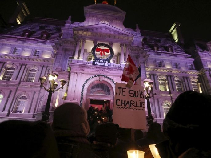 People participate in a vigil to pay tribute to the victims of a shooting, by gunmen at the offices of weekly satirical magazine Charlie Hebdo in Paris, in front of City Hall in downtown Montreal, January 7, 2015. Hooded gunmen stormed the Paris offices of the weekly satirical magazine known for lampooning Islam and other religions, shooting dead at least 12 people, including two police officers, in the worst militant attack on French soil in decades. Placard reads "I am Charlie". REUTERS/Christinne Muschi (CANADA - Tags: CIVIL UNREST CRIME LAW)