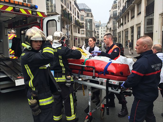 Firefighters carry an injured man on a stretcher in front of the offices of the French satirical newspaper Charlie Hebdo in Paris on January 7, 2015, after armed gunmen stormed the offices leaving at least one dead according to a police source and "six seriously injured" police officers according to City Hall.