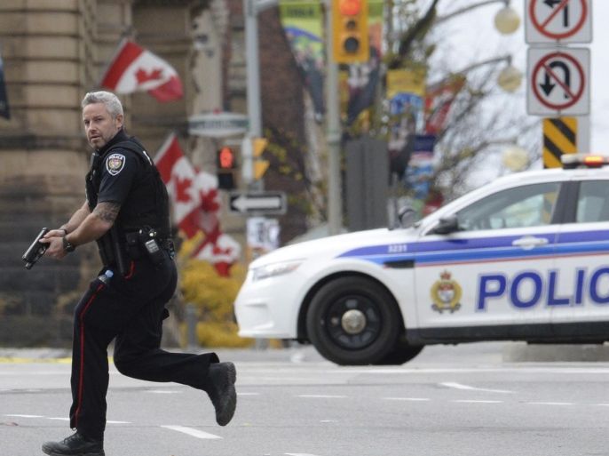 FILE - In this Wednesday, Oct. 22, 2014 file photo, an Ottawa police officer runs with his weapon drawn outside Parliament Hill in Ottawa. Radical Muslim Michael Zehaf-Bibeau killed a soldier outside Canada's parliament. Right-wing extremist Larry McQuilliams opened fire on buildings in Texas’ capital and tried to burn down the Mexican Consulate. Al-Qaida-inspired Michael Adebowale and an accomplice hacked an off-duty soldier to death in London. Police said the three perpetrators of recent attacks were terrorists and motivated by ideology. Authorities and family members said they may have been mentally ill. (AP Photo/The Canadian Press, Sean Kilpatrick, File)