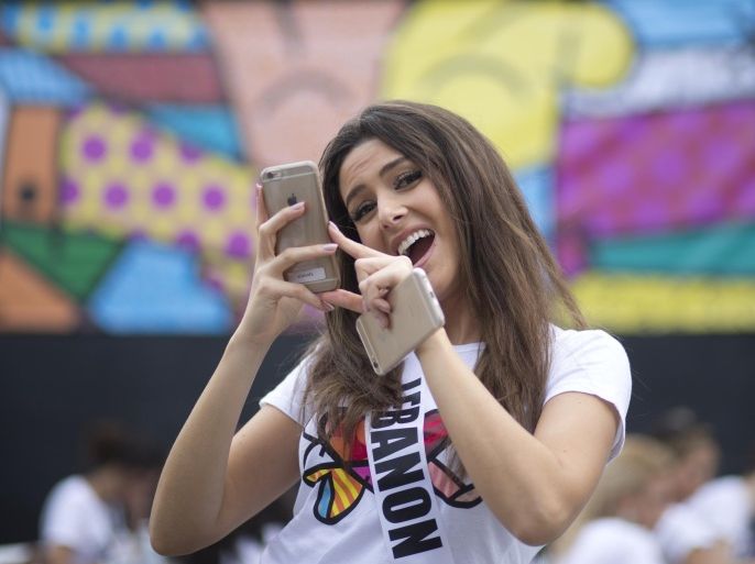 Miss Lebanon, Saly Greige, poses for photos after she painted on a wall in Miami's Wynwood area, Sunday, Jan. 11, 2015. Miss Universe contestants visited pop artist Romero Britto’s studio for an interactive painting event. (AP Photo/J Pat Carter)