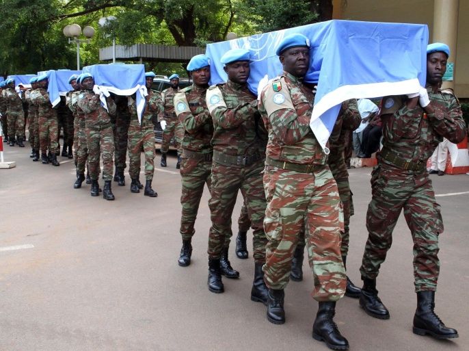 MINUSMA's soldiers, the UN mission in Mali, carry the coffins of nine UN soldiers draped with UN flags during a service at the headquarters of MINUSMA on October 7, 2014 in Bamako. The soldiers, all from Niger, were on a supply run in the north-eastern desert on October 3, 2014 when they were targeted by armed men on motorbikes. AFP PHOTO / HABIBOU KOUYATE