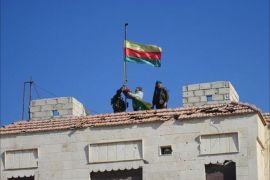 مسلحون أكراد يرفعون علم حزب العمال الكردستاني على مخفر تابع للنظام السوري شمال مدينة الحسكة بعد السيطرة عليه