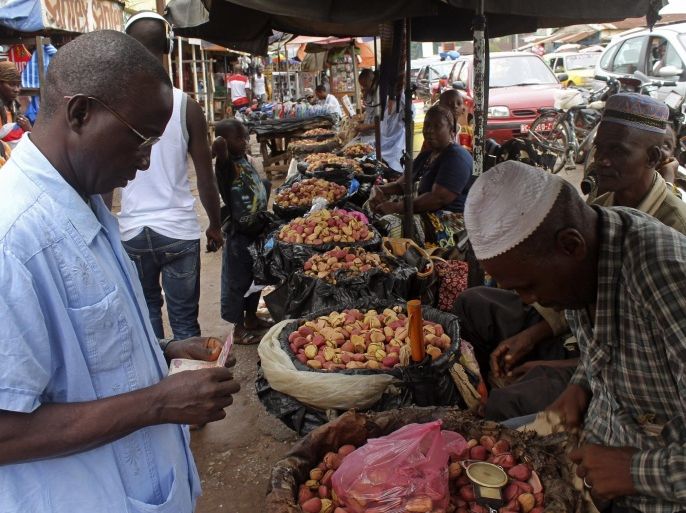 A customer purchases goods from a food stall at a local market in the city of Conakry, Guinea, Friday, Aug. 15, 2014. The deadly Ebola virus that has killed more than 1,000 in West Africa is disrupting the flow of goods, forcing the United Nations to plan food convoys for up to a million people as hunger threatens the largely impoverished area. (AP Photo/ Youssouf Bah)