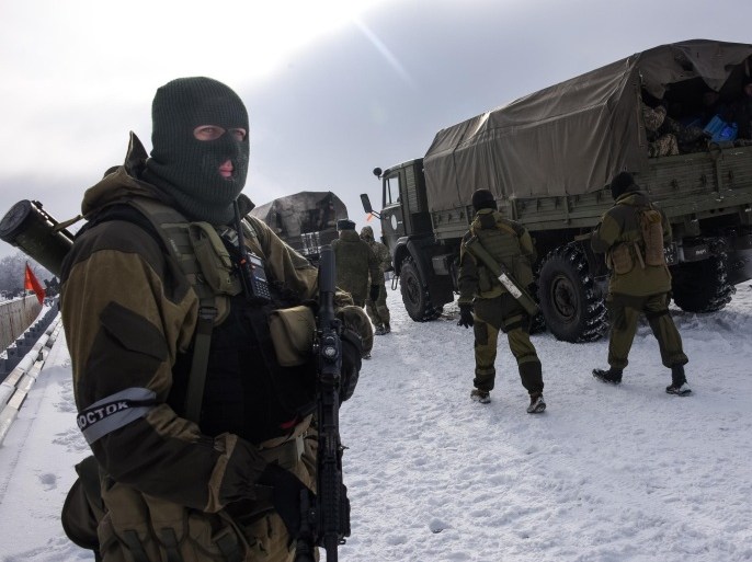 A pro-Russian rebel guards the road near the Airport of Donetsk as the other two patrol Ukrainian military vehicles behind him, Eastern Ukraine, Tuesday, Jan. 6 , 2015. Ukrainian soldiers took up duties Tuesday at the Donetsk Airport, which has been the scene of some of the fiercest fighting in eastern Ukraine. The 50 soldiers in a convoy of four trucks were provided safe passage to the airport by rebel forces, who gave them gifts in celebration of Orthodox Christmas. (AP Photo/Mstyslav Chernov)