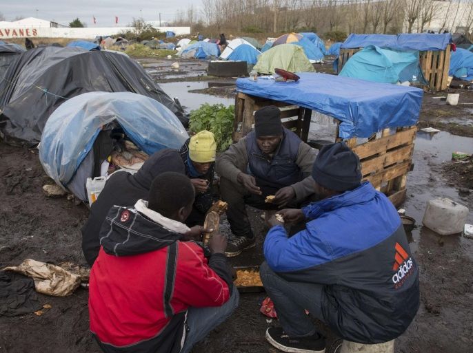 Sudanese migrants eat a meal near tents and makeshift shelters at a camp in Calais, December 17, 2014. Roughly 2,300 immigrants, many of them from Africa, are roaming the streets and sleeping in makeshift camps in and around Calais while waiting to attempt the final leg of their bid to reach Britain, according to estimates from the local prefect's office. Britain and France have agreed to improve border controls and cooperate more closely in an effort to control a growing number of illegal immigrants trying to cross the English Channel from the French port city of Calais to Britain. On December 18, the International Migrants Day, the international community recognises and celebrates the rights of migrants around the world.REUTERS/Philippe Wojazer (FRANCE - Tags: SOCIETY IMMIGRATION POLITICS)