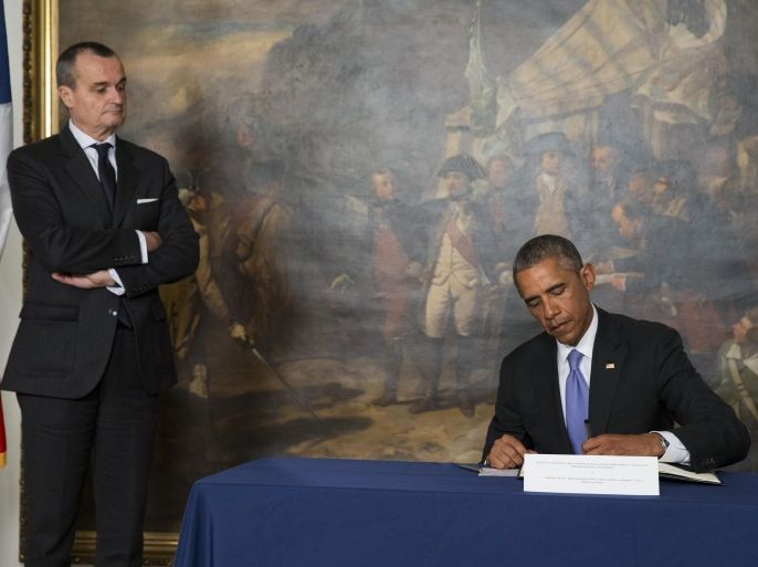 French Ambassador to the United States Gerard Araud, left, looks on as President Barack Obama signs a condolences book during a visit to the French Embassy, on Thursday, Jan. 8, 2015, in Washington. Masked gunmen stormed the Paris offices of a weekly newspaper that caricatured the Prophet Muhammad, killing at least 12 people, including the editor, before escaping in a car. It was France's deadliest postwar terrorist attack. (AP Photo/Evan Vucci)