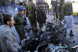 SANAA, YEMEN - JANUARY 07 : Yemenis gather around the wreckage of a car at the site of a car bomb explosion outside a police academy in Sanaa, Yemen on January 7, 2015. Dozens were killed in a car bomb explosion on January 07, 2014 outside a police academy in Yemeni capital Sanaa.