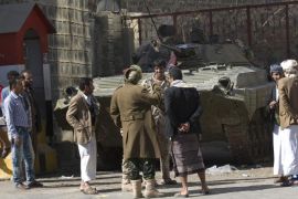 People and Houthi Shiite Yemeni wearing army uniforms stand near an armored vehicle, which was seized from the army during recent clashes, outside the house of Yemen's President Abed Rabbo Mansour Hadi in Sanaa, Yemen, Thursday, Jan. 22, 2015. Heavily armed Shiite rebels remain stationed outside the Yemeni president's house and the palace in Sanaa, despite a deal calling for their immediate withdrawal to end a violent standoff. (AP Photo/Hani Mohammed)