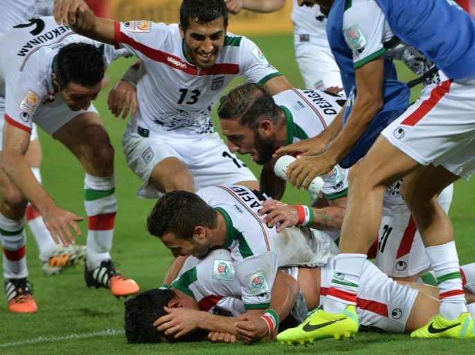 Team mates pile on to Reza Ghoochannejhad (bottom) of Iran as they celebrate Ghoochannejhad goal against the United Arab Emirates during their Group C football match at the AFC Asian Cup in Brisbane on January 19, 2015. AFP PHOTO / John PRYKE--- IMAGE RESTRICTED TO EDITORIAL USE - STRICTLY NO COMMERICAL USE --