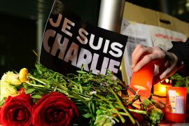 A man lights a candle next to a poster reading "Je suis Charlie" (I am Charlie) in front of the French embassy on January 7, 2015 in Berlin to express solidarity with employees of the French satirical weekly Charlie Hebdo that has been target of an attack by unknown gunmen. German Chancellor Angela Merkel condemned the "despicable" attack on Charlie Hebdo that left at least 12 people dead in a condolence letter to President Francois Hollande