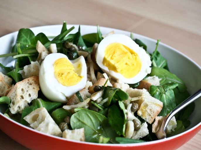 Bowl of spinach salad with hard boiled egg and croutons