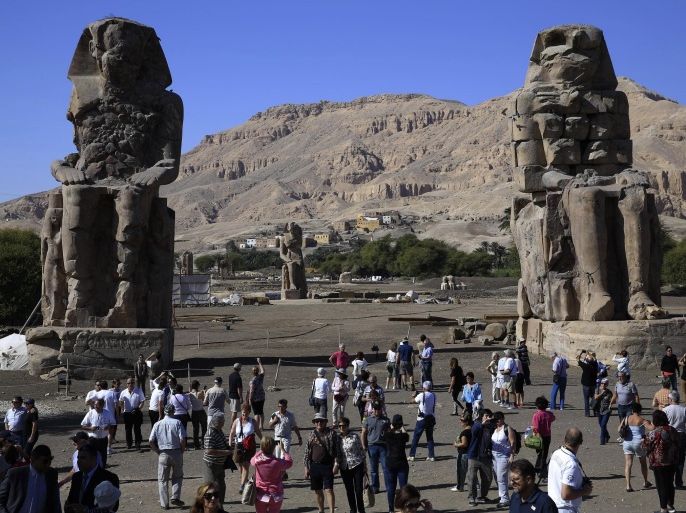 Tourists look at the Colossi of Memnon, two massive stone statues of Pharaoh Amenhotep III, on the west bank of the Nile River at Luxor, 510 kilometers (320 miles) south of Cairo, Egypt, Monday, Dec. 1, 2014. Tourism in Egypt, the lifeblood of its economy, has suffered in the years since its 2011 revolution. (AP Photo/Hassan Ammar)