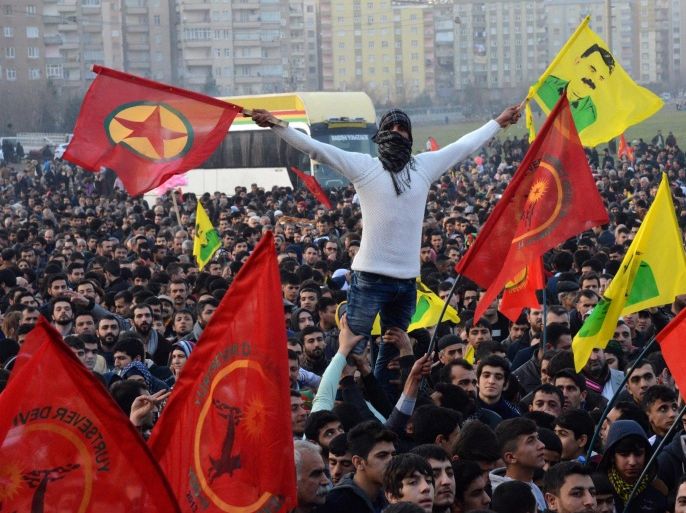A man holds a flag of the Kurdish Worker's Party (PKK) and a poster flag of jailed kurdish leader and PKK founder Abdullah Ocalan during a rally on January 27, 2015 in Diyarbakir, southeastern Turkey, following news that Kurdish fighters drove the Islamic State group from the Syrian border town of Kobane, also known as Ain al-Arab, which became a major symbol of resistance against the jihadists. AFP PHOTO / ILYAS AKENGIN