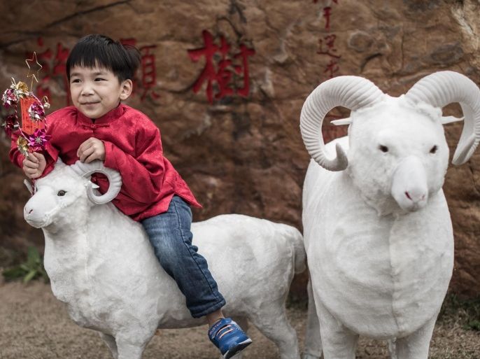 A boy stands on a model of a ram near a temple during celebrations to mark the first day of the Lunar New Year in Hong Kong on February 19, 2015. Fortune tellers in Hong Kong said that the Year of the Sheep should be calmer in general than the previous Year of the Horse, which was characterised by catastrophic international air accidents, brutal terror attacks, global political upheaval, a resurgent Ebola virus and war. AFP PHOTO / Philippe Lopez