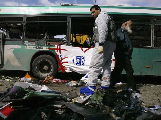 JERUSALEM, ISRAEL - FEBRUARY 22: Israeli police pass between victims' personal effects and the wreckage of a passenger bus destroyed in a suicide bombing February 22, 2004 in Jerusalem, Israel. At least seven Israelis were killed and dozens more wounded when a Palestinian attacker blew himself up on the bus packed with early morning commuters.