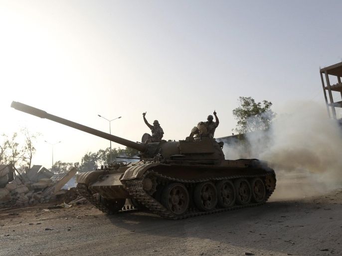 Fighters from the Benghazi Shura Council, which includes former rebels and militants from al Qaeda-linked Ansar al-Sharia, gesture on top of a tank next to the camp of the special forces in Benghazi July 30, 2014. On Wednesday, the eastern city of Benghazi was quieter after Islamist fighters and allied militia forces overran a special forces army base in the city in a major blow to a military campaign against Islamist militants there. The self-declared Benghazi Shura Council forces took over the base on Tuesday after fighting involving rockets and warplanes that killed at least 30 people. REUTERS/Stringer (LIBYA  - Tags: CIVIL UNREST POLITICS)
