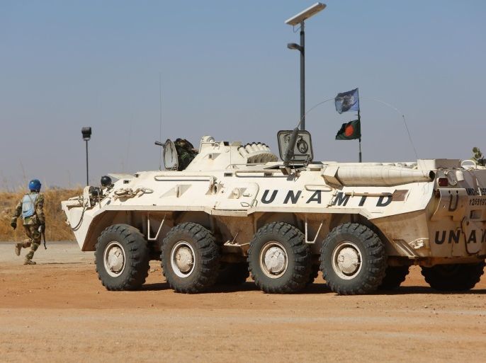 A member of the UN-African Union mission in Darfur (UNAMID) runs past an armoured personnel carrier patrolling near the city of Nyala in Sudan's Darfur on January 12, 2015. Qatar's deputy premier Ahmed bin Abdullah al-Mahmud is on a visit to the war-torn western region of Sudan for the ninth meeting of the committee monitoring the implementation of the Doha Document for Peace Darfur (DDPD). AFP PHOTO / ASHRAF SHAZLY