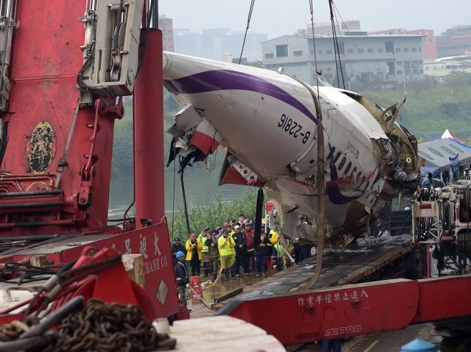 A general view shows the crashed Transasia plane wreckage being lifted onto a truck in New Taipei City on February 5, 2015. Taiwan rescuers scoured a river for 12 people still missing from a TransAsia plane crash as the pilot was hailed as a hero for apparently battling to avoid hitting built-up areas shortly after issuing a 'mayday' call. AFP PHOTO / Sam Yeh