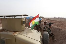 A Kurdish flag is seen next to Peshmerga fighters taking position with their weapons on the frontline against the Islamic State, on the outskirts of Mosul January 26, 2015. Kurdish Peshmerga fighters are digging trenches and building defense berms in Wadi al-Ghorab (Valley Of The Crows), less than 2 km away from the IS-held Sultan Abdullah village, which demarcates the new border of their autonomous region. The Kurds have enjoyed de facto self rule since the first Gulf War in 1991. They are now closer than ever to achieving their dream of full independence. Yet they are menaced by the deadly ambitions of the Islamic caliphate across the frontline. Picture taken January 26, 2015. REUTERS/Azad Lashkari (IRAQ - Tags: CIVIL UNREST CONFLICT MILITARY POLITICS)