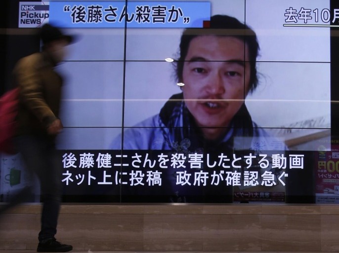 A pedestrian walks past television screens displaying a news program about Japanese journalist Kenji Goto, who was held hostage by Islamic State militants, on a street in Tokyo February 1, 2015. Islamic State militants said they had beheaded a second Japanese hostage, journalist Kenji Goto, prompting Abe to vow to step up humanitarian aid to the group's opponents in the Middle East and help bring his killers to justice. The words on the screen (top L) read, "Goto was murdered ?" REUTERS/Yuya Shino (JAPAN - Tags: POLITICS CIVIL UNREST)