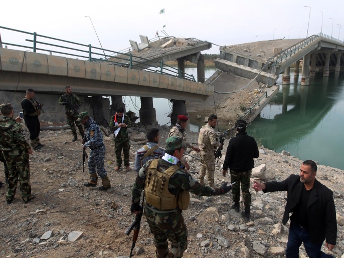 عناصر من الحشد الشعبي عند جسر مدمر يربط الفلوجة ببغداد (غيتي/الفرنسية)