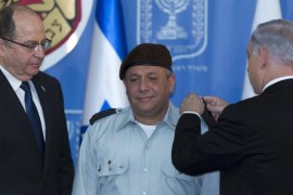Israeli Prime Minister Benjamin Netanyahu (R) places an epaulet on the shoulder of the new Israeli Chief of Staff, Lieutenant General Gadi Eisenkot as Defense Minister Moshe Ya'alon (L) looks on during a changeover ceremony in the Jerusalem offices of the prime minister, 16 February 2015. Eisenkot, born in the Sea of Galilee town of Tiberias, Israel is 54 and is the 21st Israeli Chief of Staff. He comes from an army infantry background.